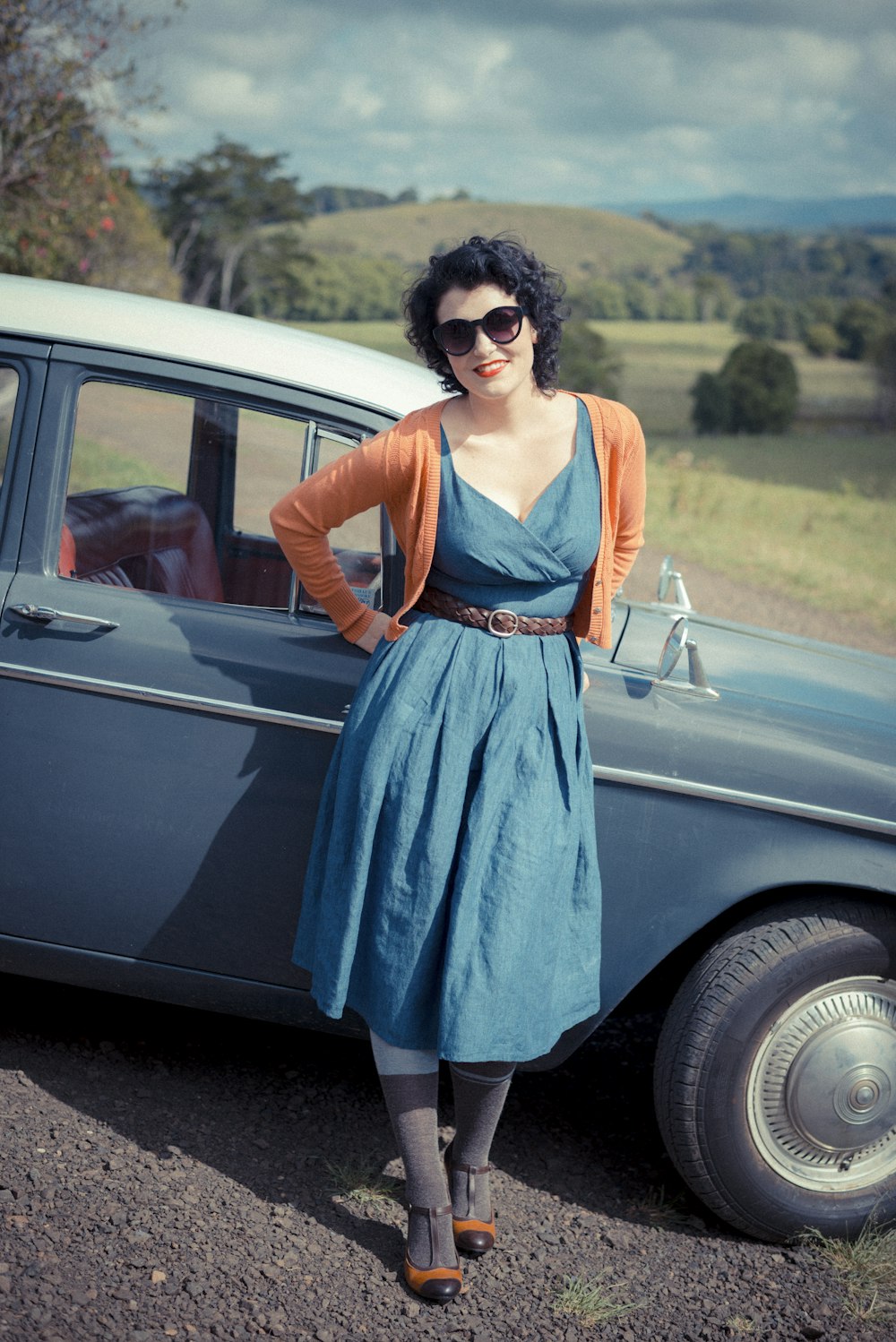 woman leaning on blue car
