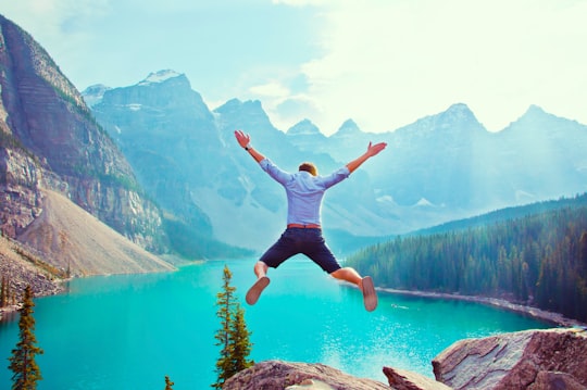photo of man about to jump from cliff in Moraine Lake Canada