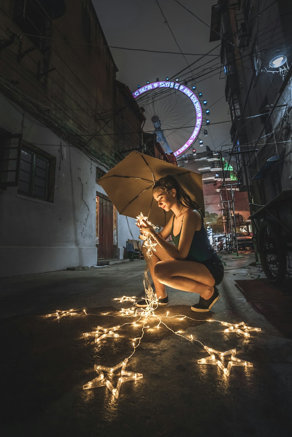 Femme tenant un parapluie et des guirlandes lumineuses pendant la nuit