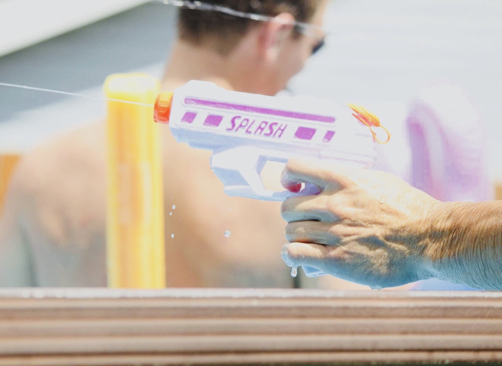 person holding pink and white Splash water gun