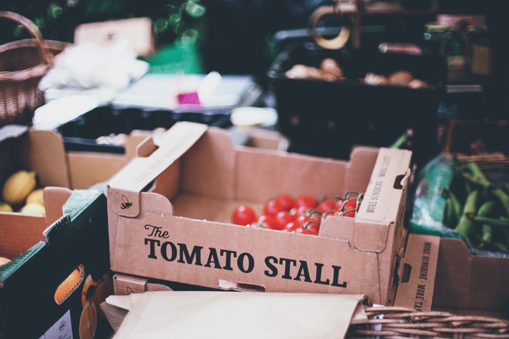 selective photography of tomato stall box on crate