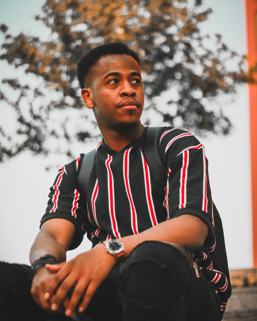 closeup photo of man sitting on black, red, and white striped V-neck t-shirt