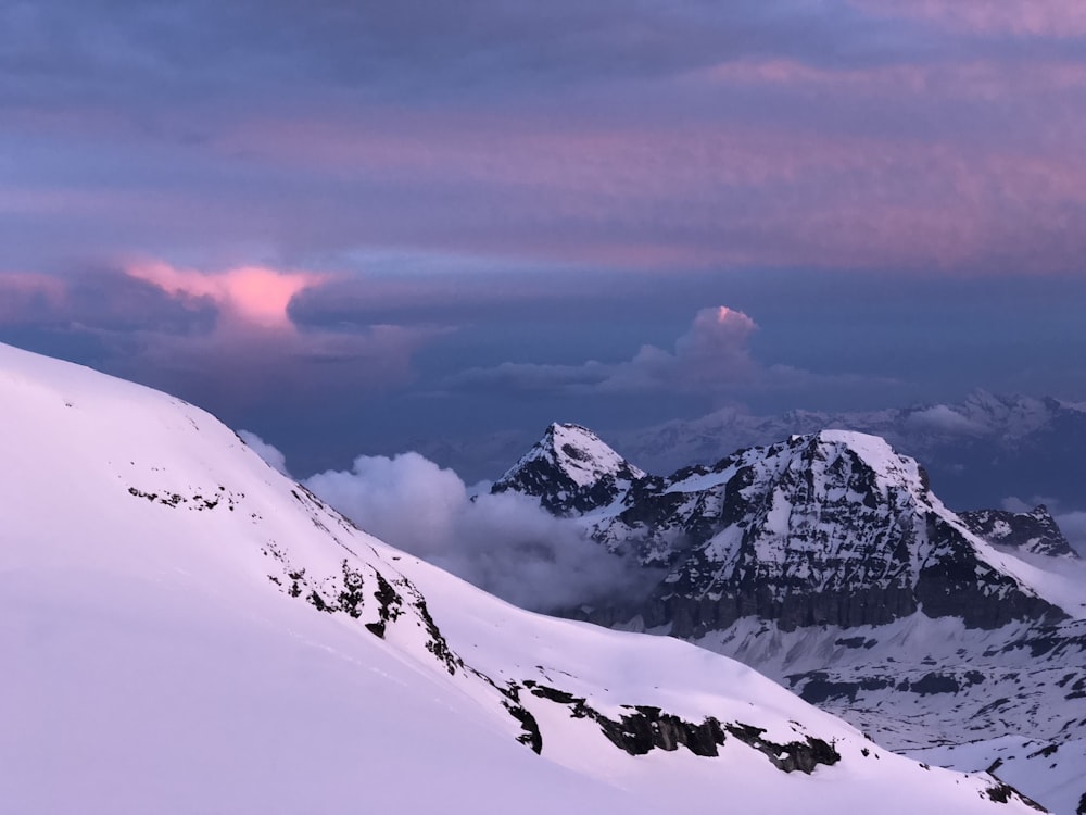 a mountain covered in snow under a cloudy sky