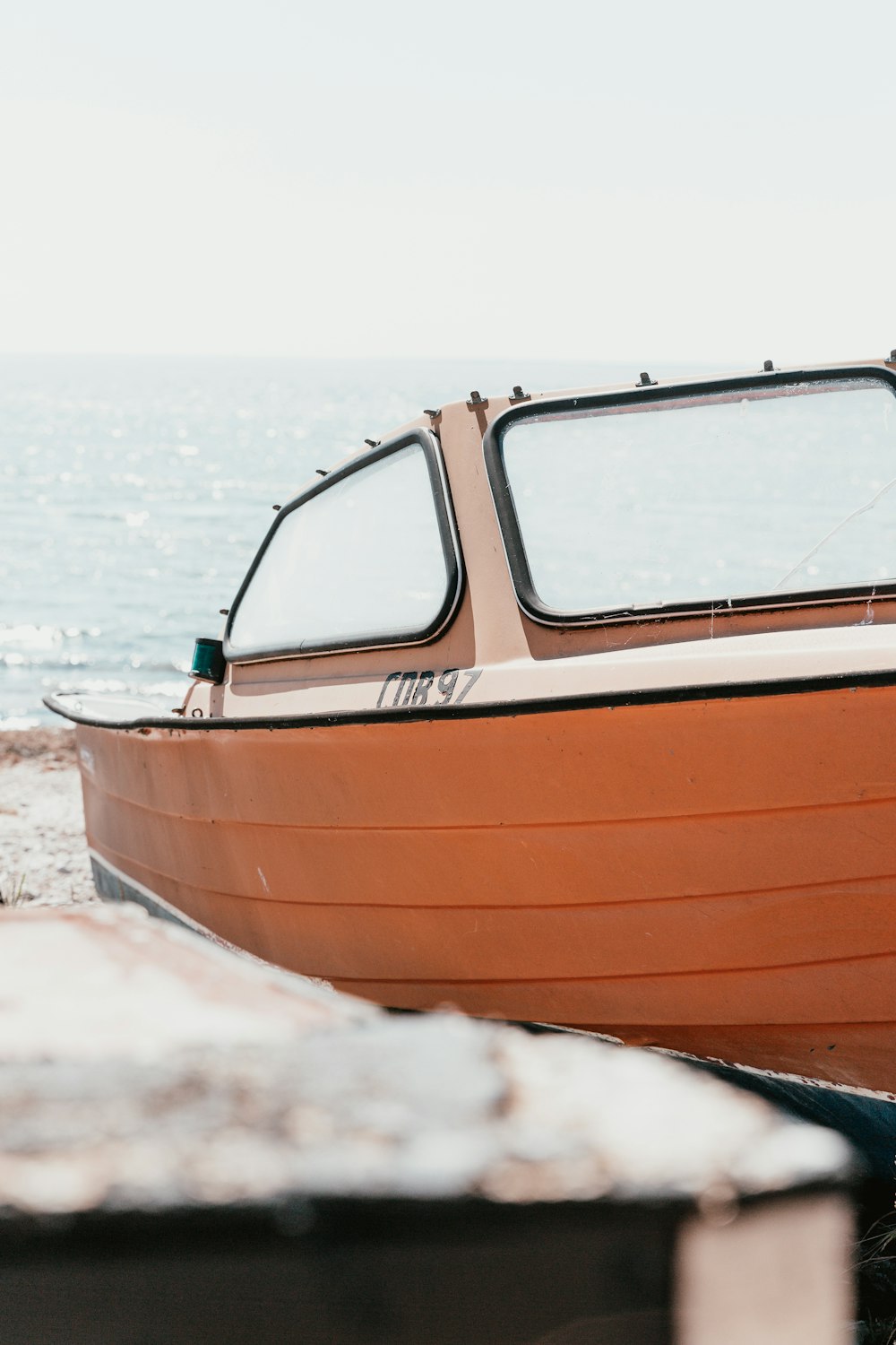 um barco sentado no topo de uma praia ao lado do oceano