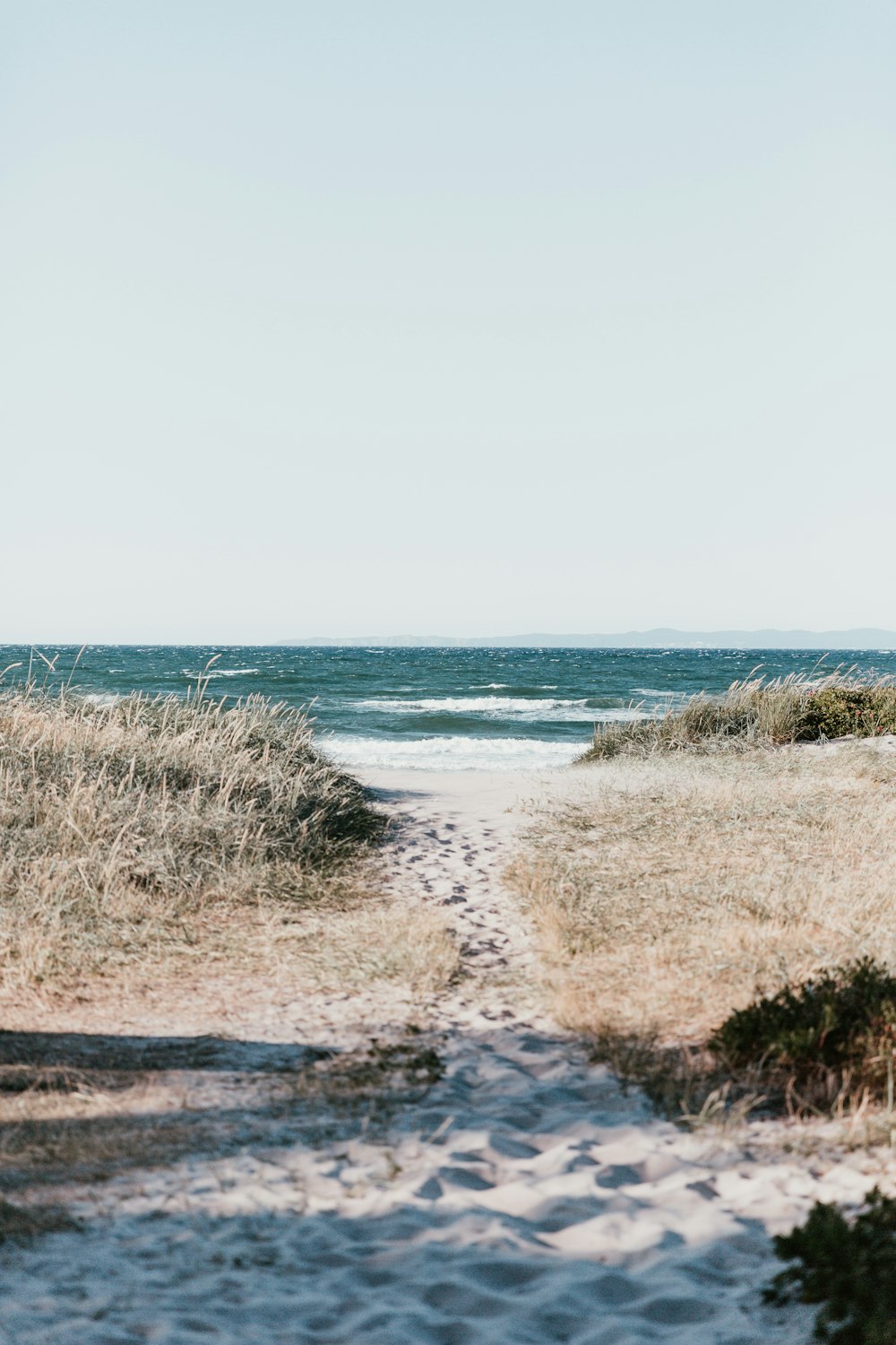 Weißer Sand mit Fußabdrücken in der Nähe des Gewässers am Tag