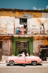 person standing beside of pink convertible car