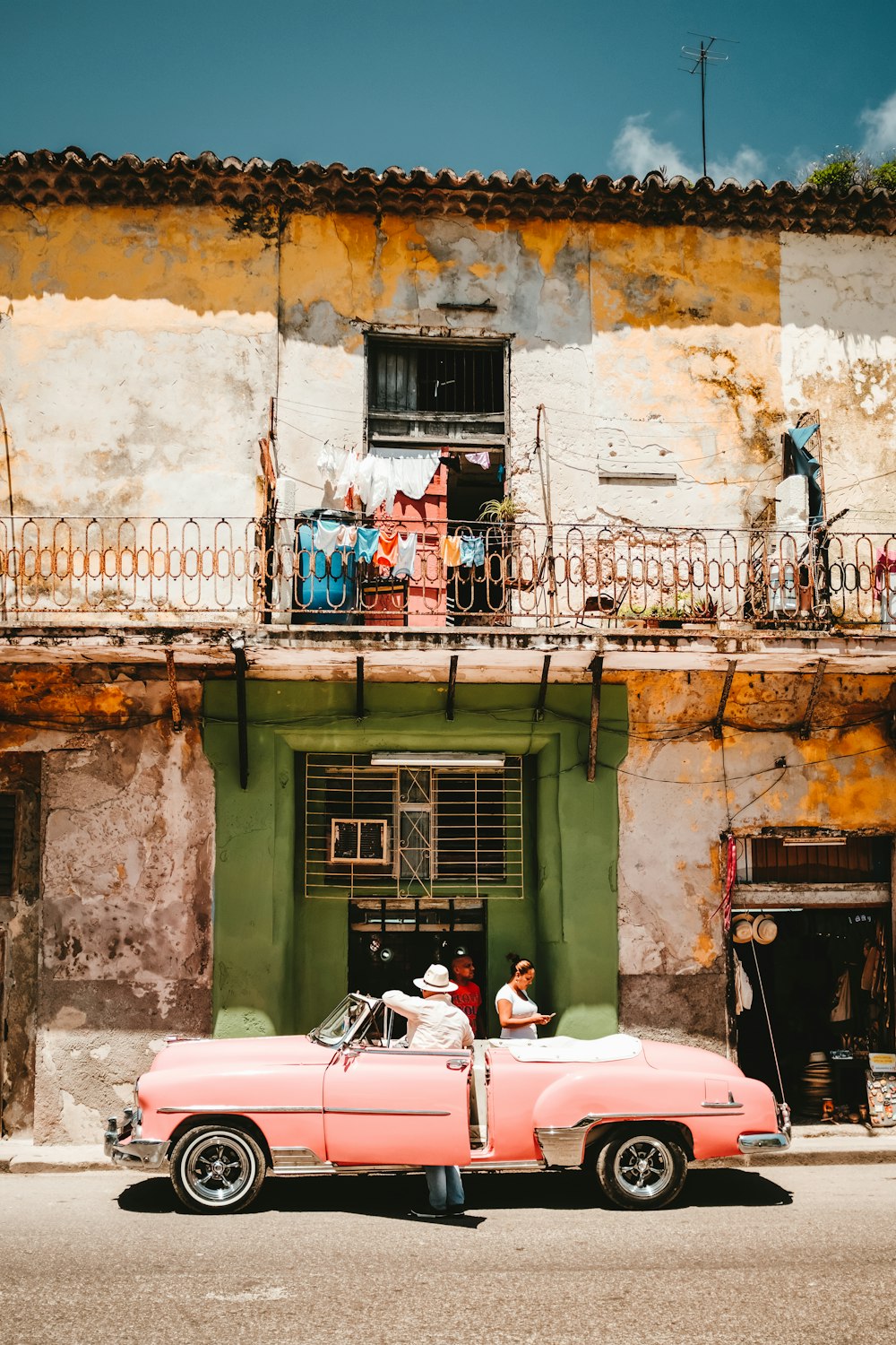 person standing beside of pink convertible car