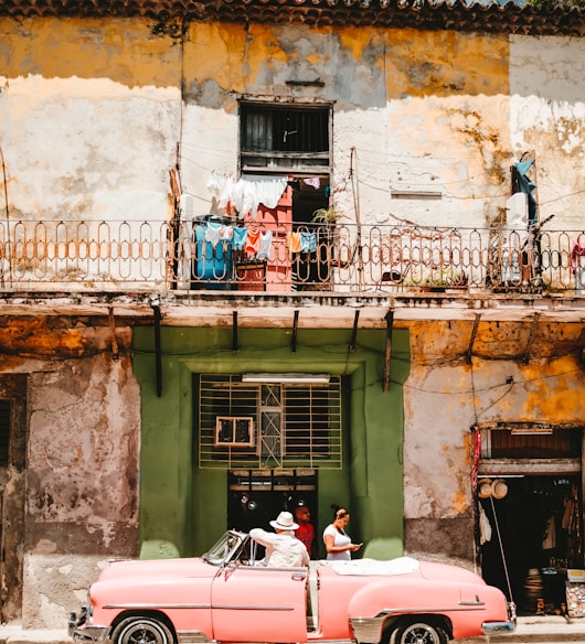 person standing beside of pink convertible car