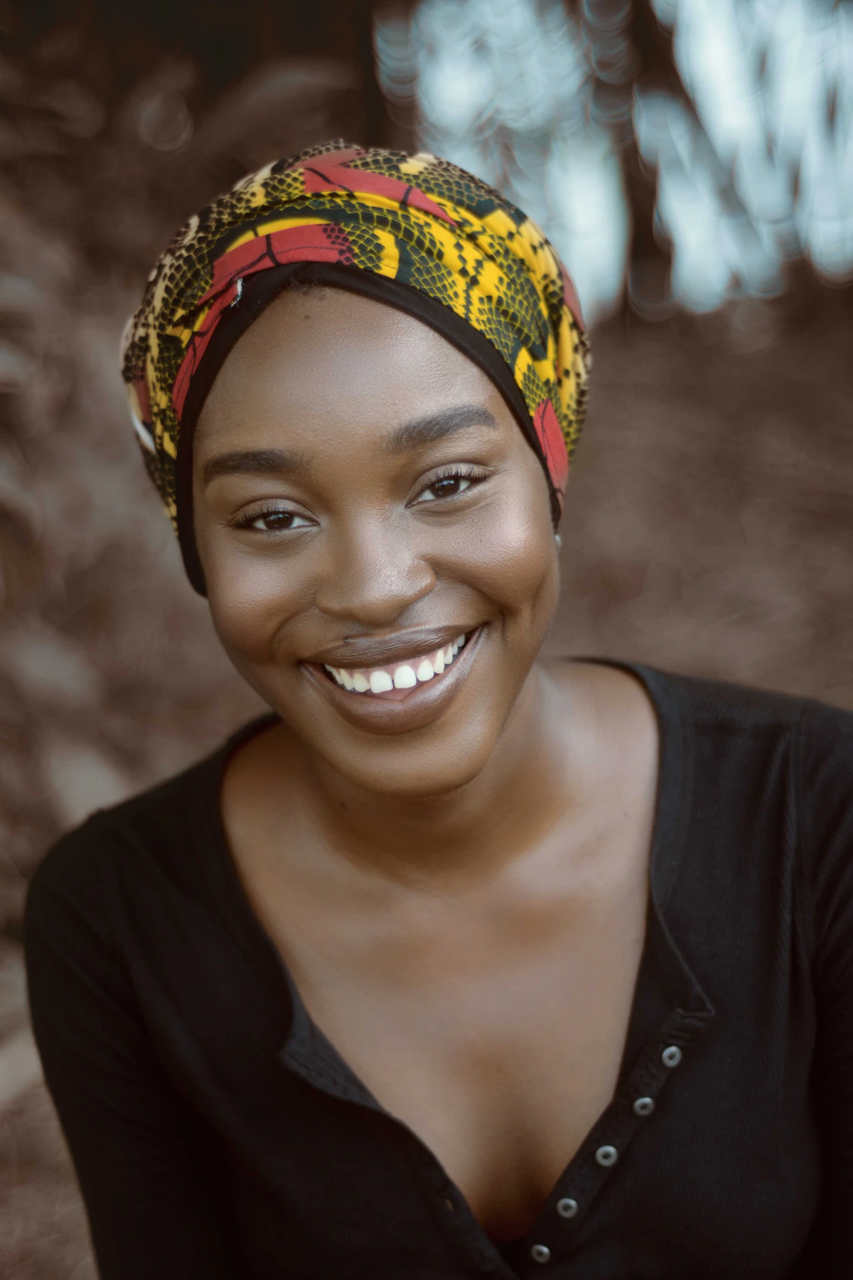 A smiling Nigerian woman wearing a colorful head wrap