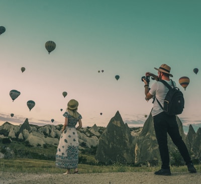 man taking photo of hot air balloons