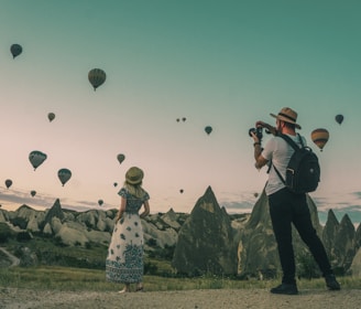 man taking photo of hot air balloons