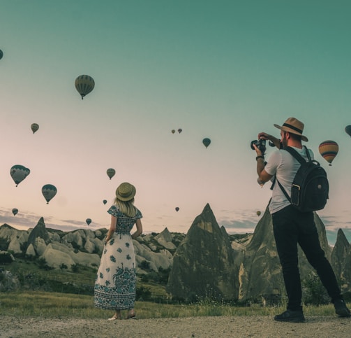 man taking photo of hot air balloons