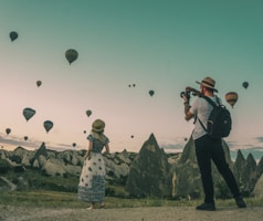 man taking photo of hot air balloons