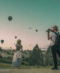 man taking photo of hot air balloons