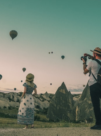 man taking photo of hot air balloons