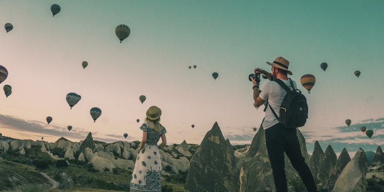 man taking photo of hot air balloons