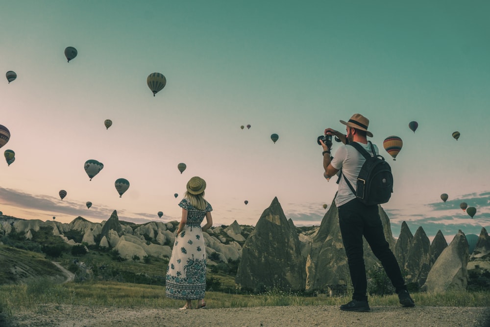 man taking photo of hot air balloons