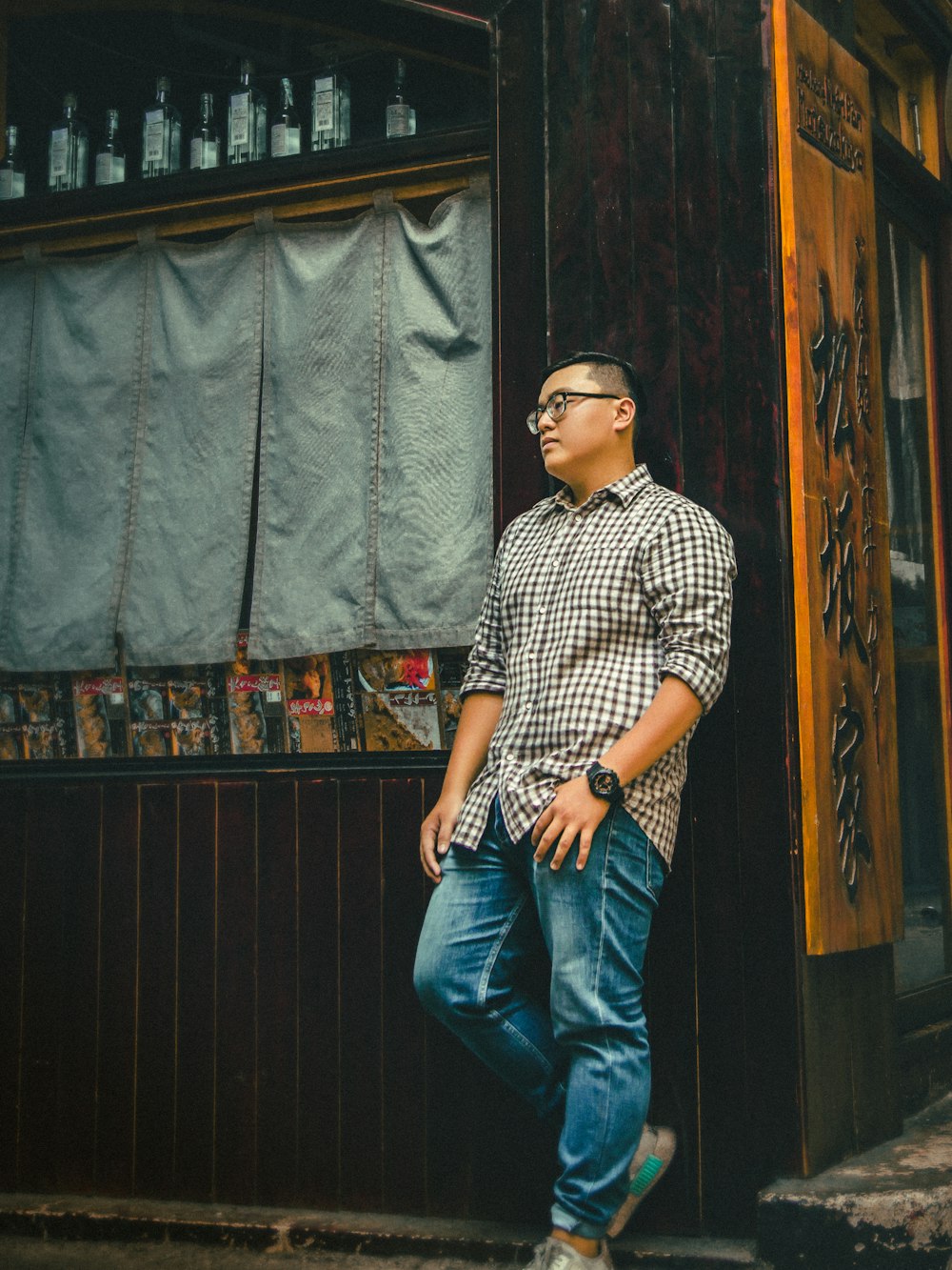 man in brown dress shirt leaning on wooden wall