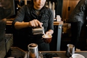 Barista carefully pouring latte art in a warm, vintage-inspired coffee shop setting.