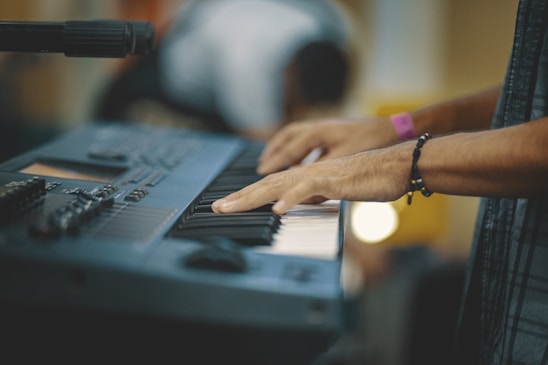 Person playing keyboard with focused expression in a cozy music school setting