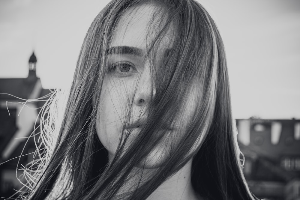 Foto in scala di grigi di donna che si copre il viso sui propri capelli