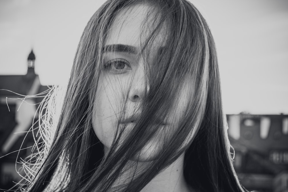 Foto en escala de grises de una mujer que se cubre la cara con su propio cabello