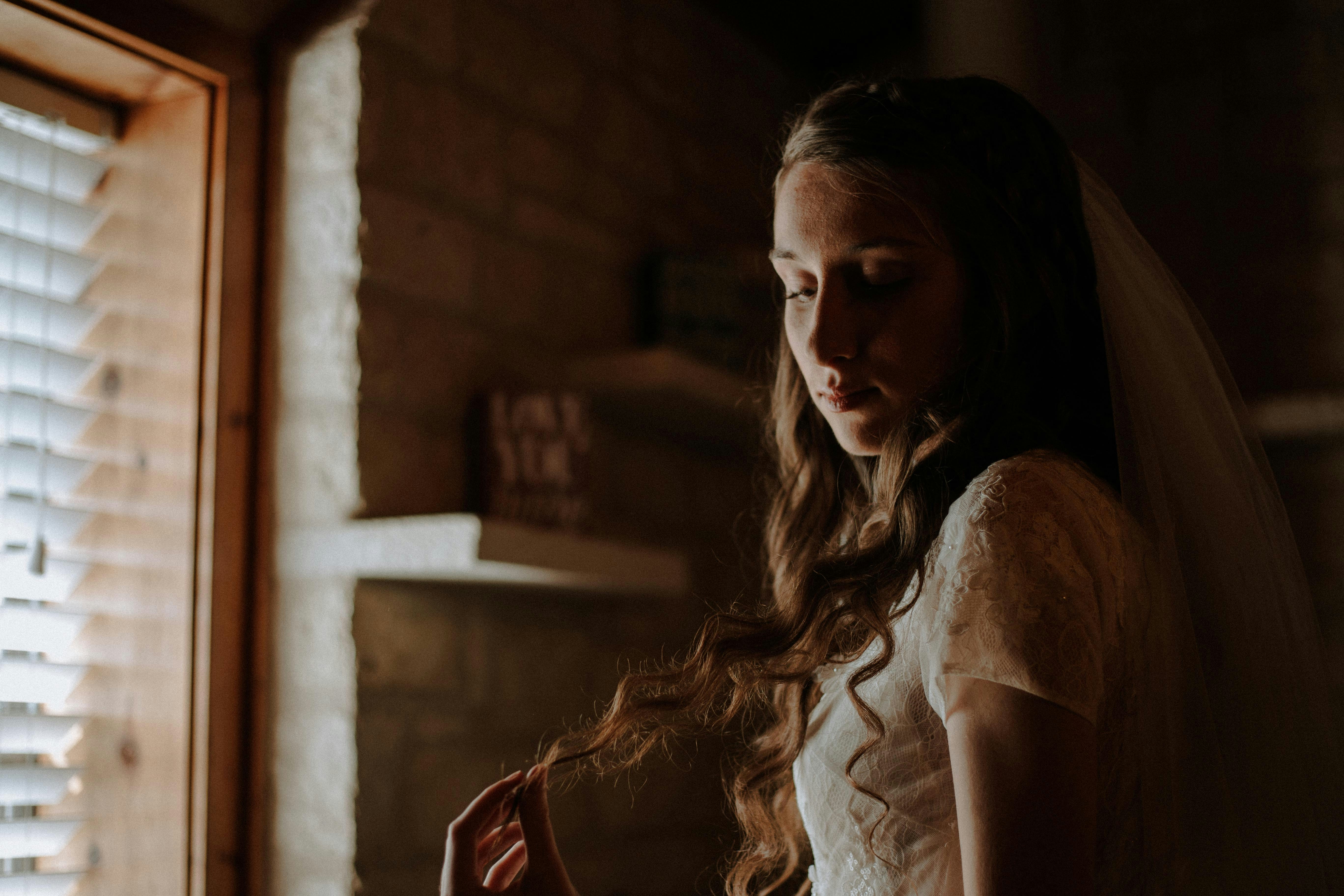 a woman in a wedding dress standing in front of a window