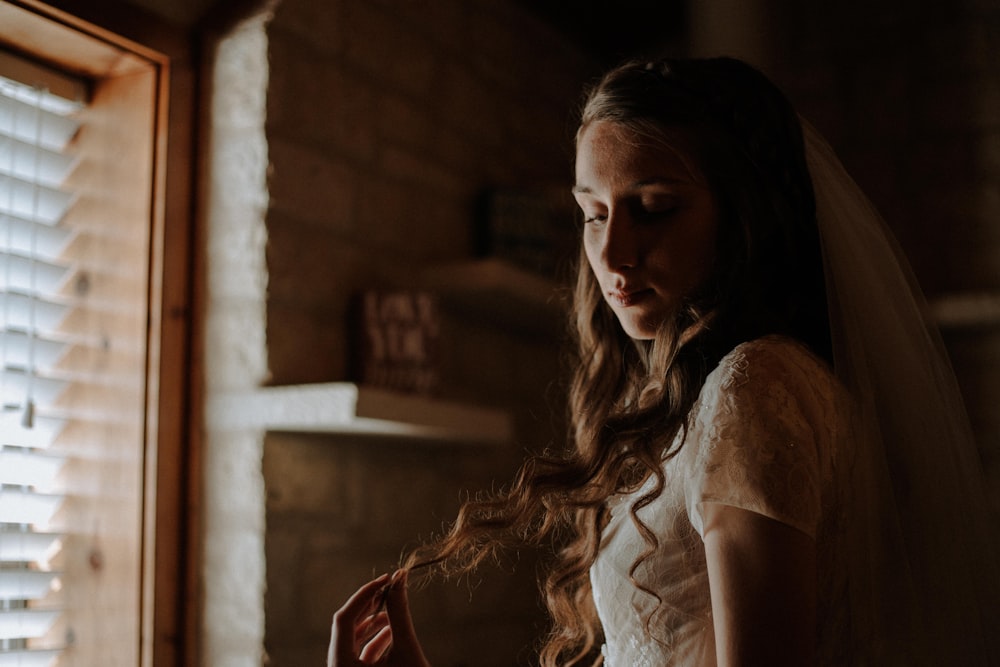 a woman in a wedding dress standing in front of a window