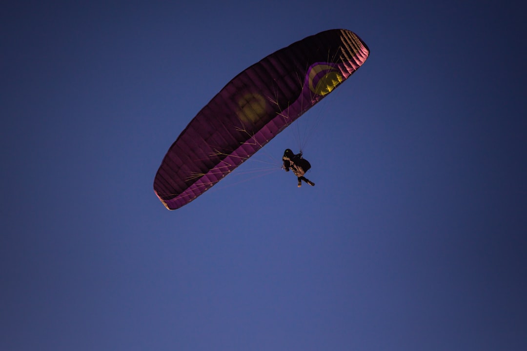 person in black shirt riding red yellow and green parachute