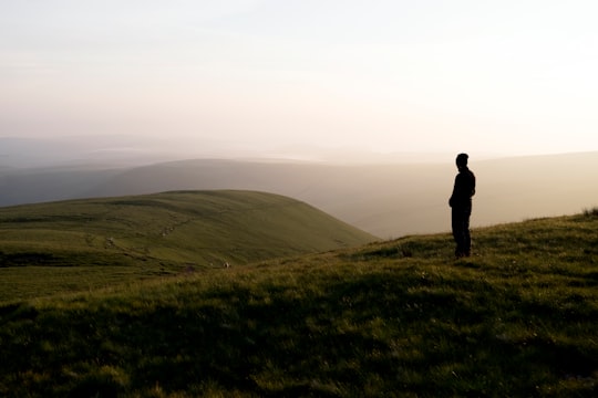 man standing on hill covered with grass in Llyn y Fan Fach United Kingdom