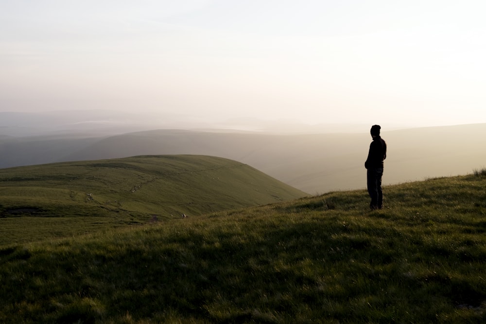 Mann steht auf einem mit Gras bedeckten Hügel