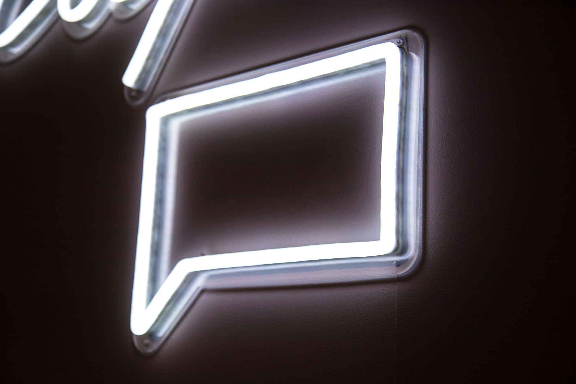 white neon light signage on wall like a social media chat bubble