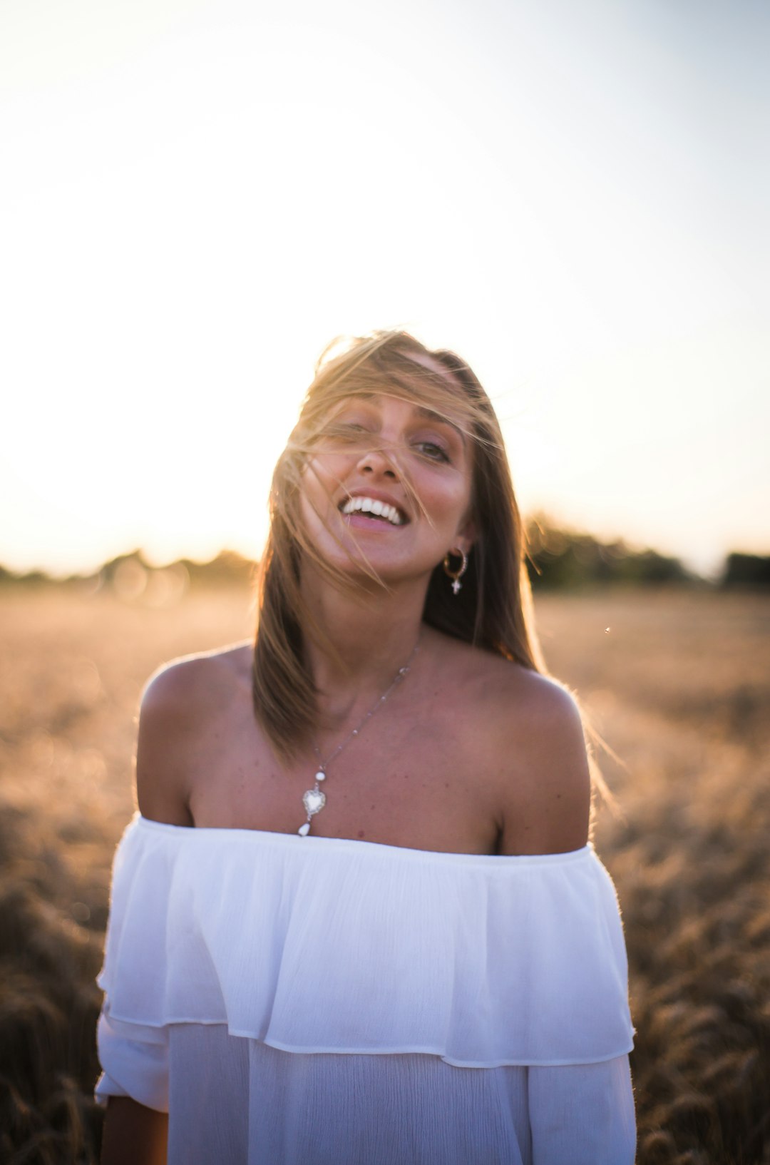 photo of smiling woman wearing white tube-top dress