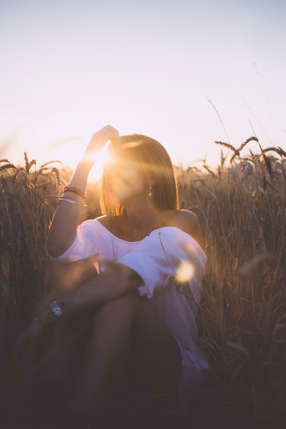 Mujer sentada en el campo de hierba durante la puesta del sol