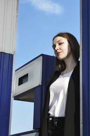 Technician inspecting fuel pump equipment at a modern petrol station under clear skies.
