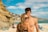 woman wearing sunglasses and bikini front of man standing near seashore