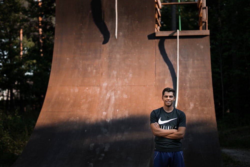 man standing behind brown wall