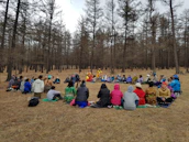 A group of diverse people sitting in a circle outdoors, sharing a moment of spiritual connection.