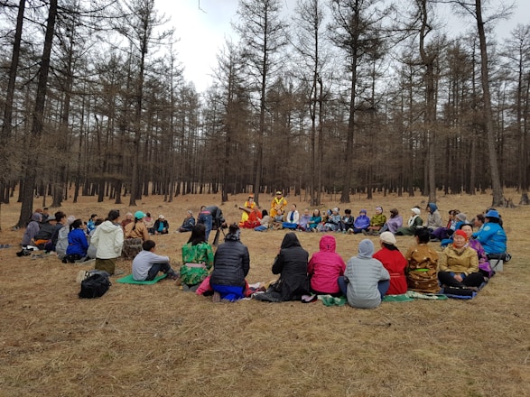 A diverse group of people sitting in a circle outdoors, engaged in a mindful discussion during a community retreat.