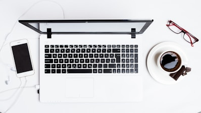 MacBook Pro between smartphone and teacup on white surface