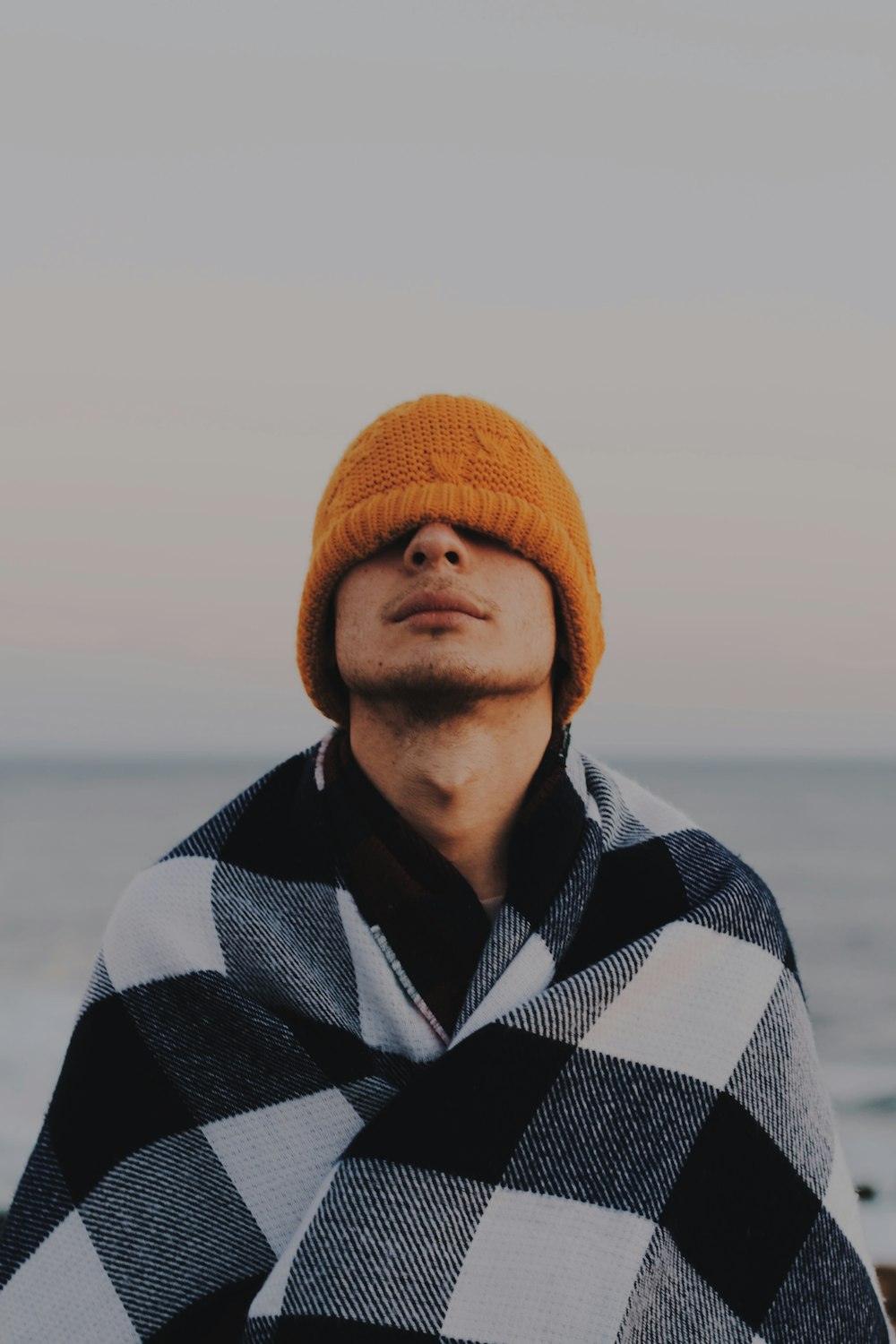 person covering his face by orange knit cap