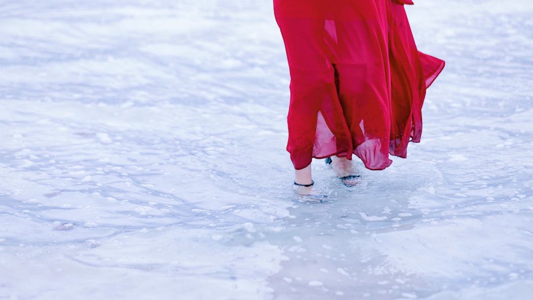 woman in red dress stepping on a body of water