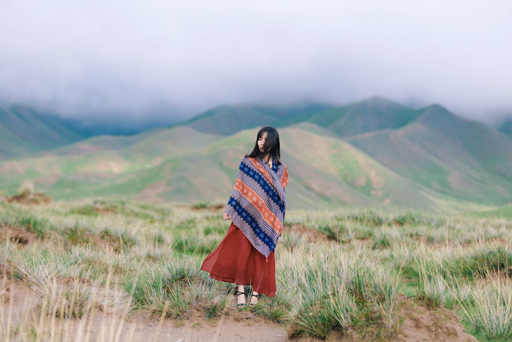 woman standing on green grass on top of mountain