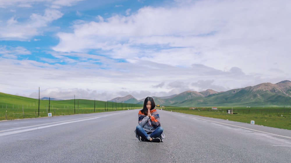 woman sitting on gray concrete road