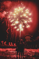 A silhouette of a bride and groom watching a dazzling fireworks and drone show.