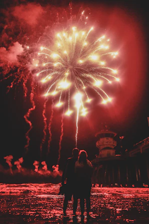 A silhouette of a bride and groom watching a dazzling fireworks and drone show.