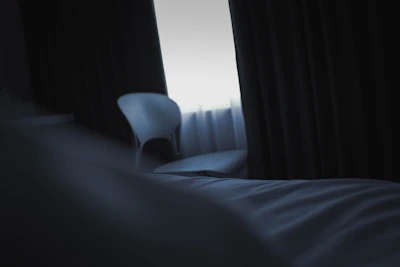 A softly lit elegant room setting with a velvet chair and subtle shadows.