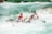 A group of four people are intensely focused as they navigate a raft through powerful whitewater rapids. They are wearing protective helmets and life jackets, showing determination and teamwork as they paddle through the churning water.