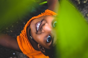 A close-up portrait capturing the genuine smile of a young child in a sunlit park.