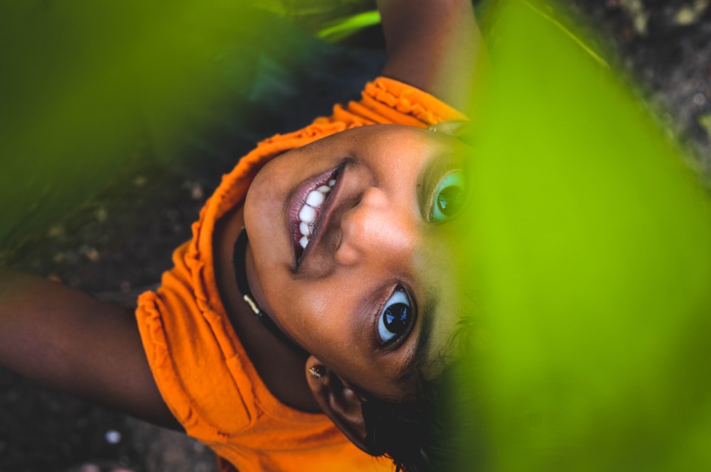 ragazza sorridente sotto le foglie verdi